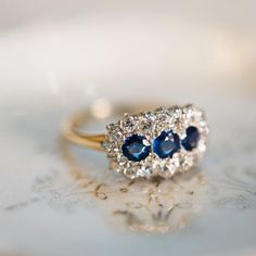 two blue and white stones sit on top of a gold ring with diamond trimmings