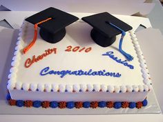 two graduation caps on top of a cake with congratulations written in blue and orange frosting