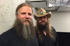 two men with long hair and beards standing next to each other in a bathroom