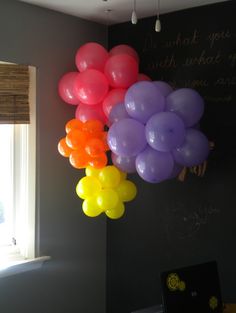 balloons are hanging from the ceiling in front of a chalkboard with writing on it