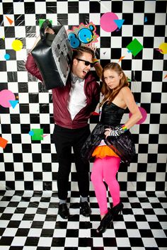 a man and woman posing for a photo in front of a black and white checkered wall