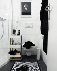 an instagram photo of a white bathroom with black and white rugs on the floor