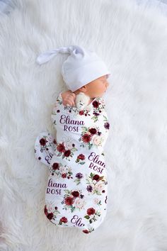 a newborn baby wrapped in a blanket and wearing a white hat with flowers on it