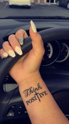 a woman's wrist with the words think positive tattooed on her left arm and an arrow