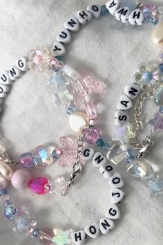 two bracelets with words and charms on them sitting on a white cloth covered surface