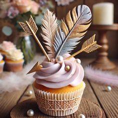 a cupcake with pink frosting and gold leaves on top is sitting on a wooden table