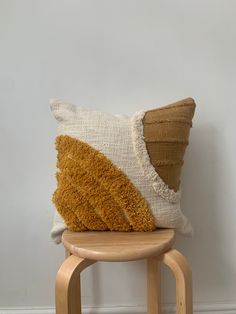 a brown and white pillow sitting on top of a wooden stool