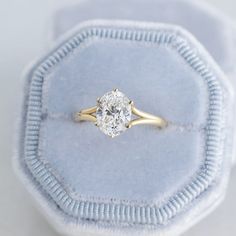 an engagement ring with a diamond in it on a blue velvet cushioned box,