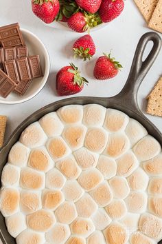 a pan filled with marshmallows and strawberries on top of a table