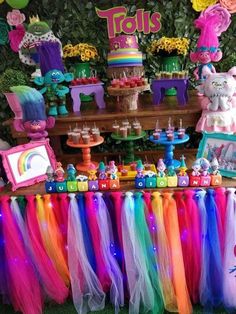 there is a table with many items on it and decorations around the table in rainbow colors