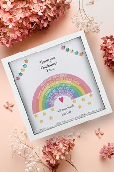 a white box with a rainbow and stars on it next to some pink flower stems