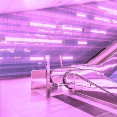 an escalator in a subway station with tiled walls and purple lighting behind it