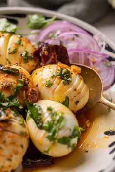 a white plate topped with scallops covered in sauce and garnished with cilantro