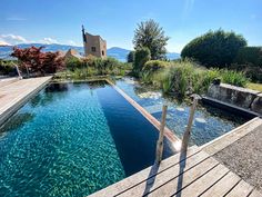 an outdoor swimming pool surrounded by wooden decking and water features with clear blue waters