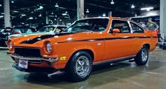 an orange car is parked in a showroom