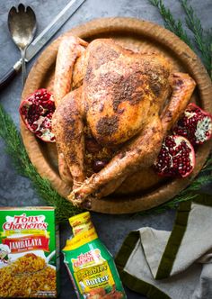 a roasted turkey on a wooden platter with pomegranates and spices