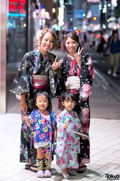 three women in kimonos posing for a photo on the street at night time