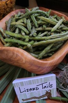 a wooden bowl filled with green beans on top of a table next to other items