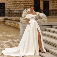 a woman in a white wedding dress standing on steps with her leg up and wearing a high slit