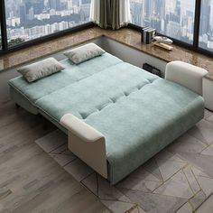 a bed sitting in the middle of a living room next to a window with city view