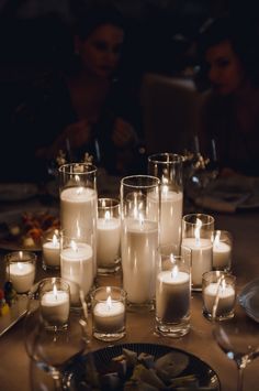 many candles are lit on a table with plates and silverware in front of them