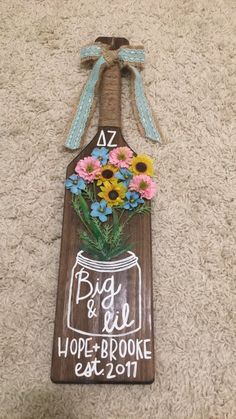 a wooden sign with flowers in a mason jar hanging on the wall next to carpet