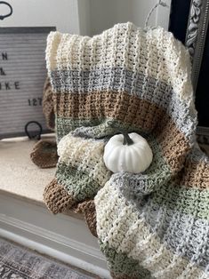 a white pumpkin sitting on top of a bed next to a blanket and pillow in front of a mirror