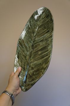 a hand holding a green leaf shaped plate