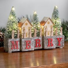 a wooden block with the word merry spelled in front of christmas trees and pine cones