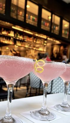 three glasses filled with pink liquid sitting on top of a white table next to each other