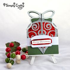 a christmas card with a red and white ornament on it next to holly berries