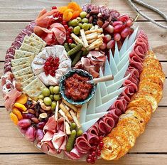 a platter filled with meats, cheeses and crackers