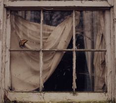 an old window with curtains in it