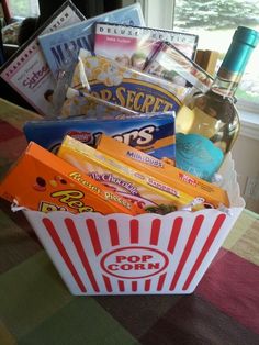 a popcorn bucket filled with snacks and wine