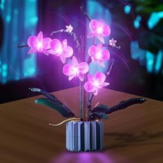 a vase with flowers in it sitting on a table next to a purple light that is shining