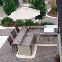 an outdoor kitchen with grill, table and chairs