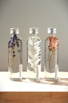 three glass bottles with dried flowers in them