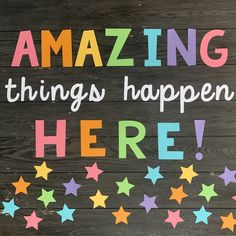 a wooden sign that says amazing things happen here with colorful stars on the wood background