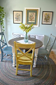 a dining room table with two chairs and a vase filled with flowers on top of it