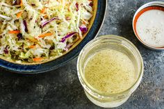 a bowl of coleslaw next to two bowls of dressing on a counter top