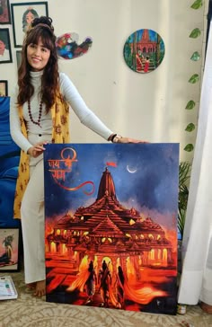 a woman holding up a painting in front of a wall