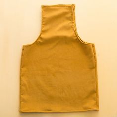 a yellow apron sitting on top of a white wall