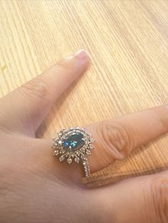 a person's hand with a ring on top of it and a wooden table in the background