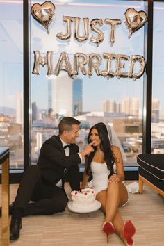 a newly married couple sitting on the floor in front of a sign that says just married