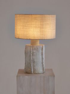 a table lamp sitting on top of a wooden block with a beige shade over it