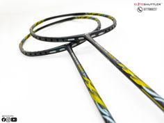 two black and yellow tennis racquets laying next to each other on a white surface