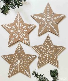 four brown paper star decorations hanging from a christmas tree