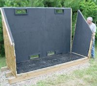 a man standing next to a large black box in the middle of some grass and trees