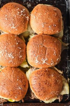 four sliders in a baking pan with shredded parmesan cheese on the top