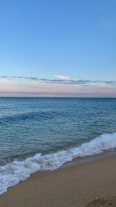 an ocean view with waves coming in to shore and blue sky above the water at sunset